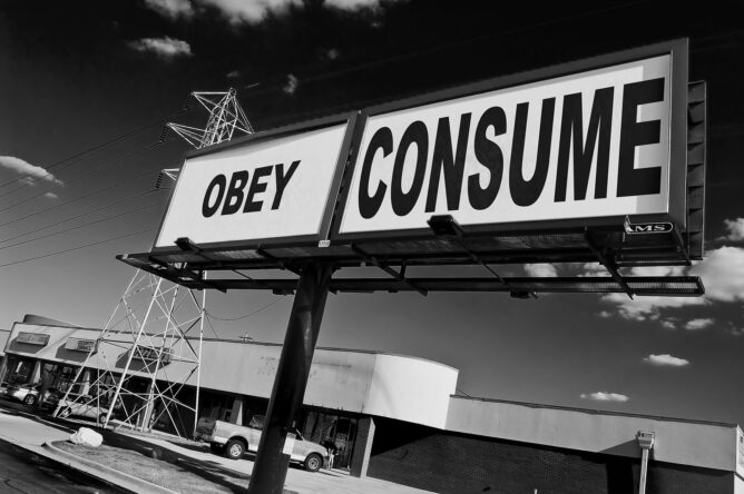Stylized grayscale image of two billboards in front of an old strip mall. One billboard shows the word "OBEY" and the other "CONSUME" in a reference to the John Carpenter film "They Live"